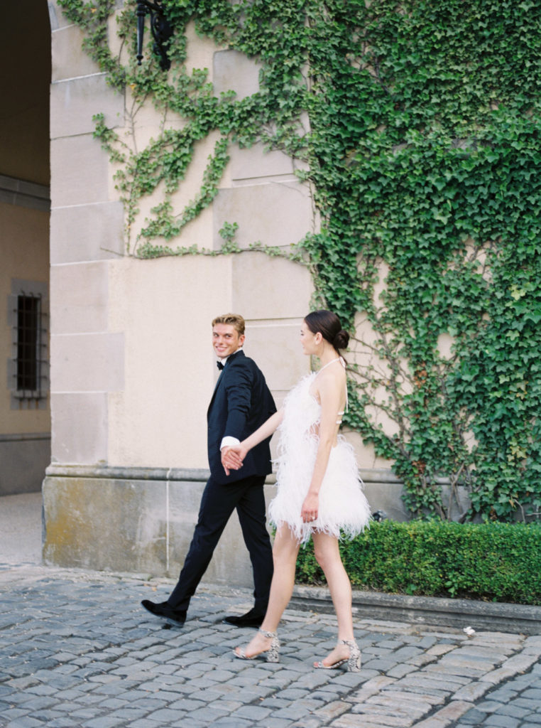 Walking hand in hand in the courtyard with the groom looking back at the bride