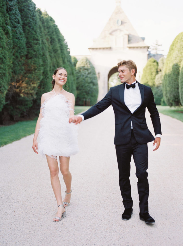 Oheka Castle Wedding venue with bride and groom holding hands down the driveway