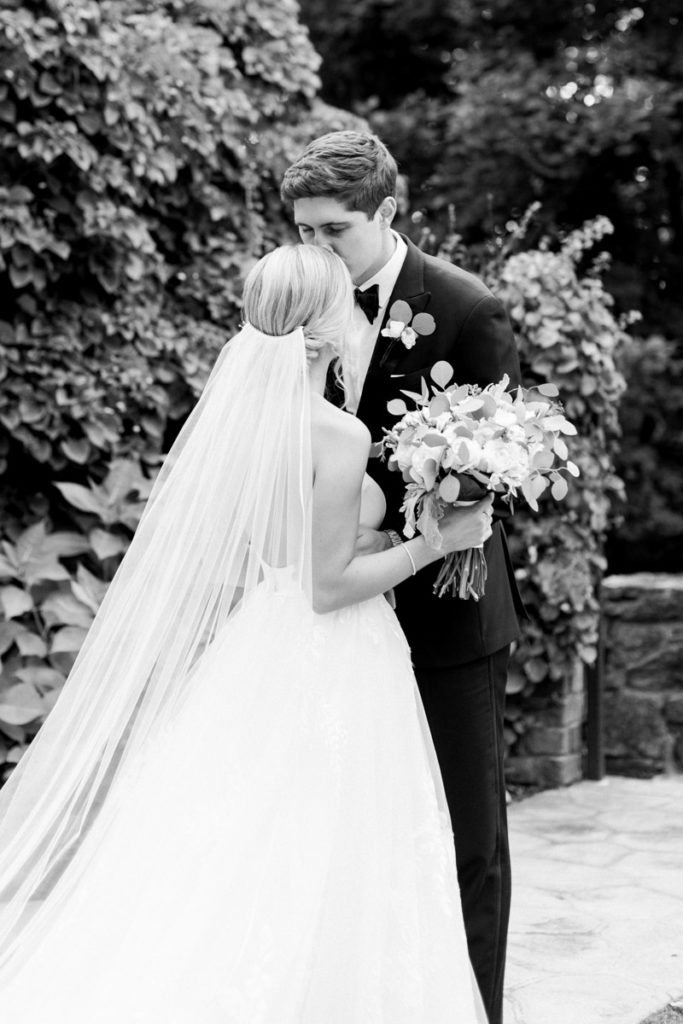 black and white of groom kissing bride on forehead