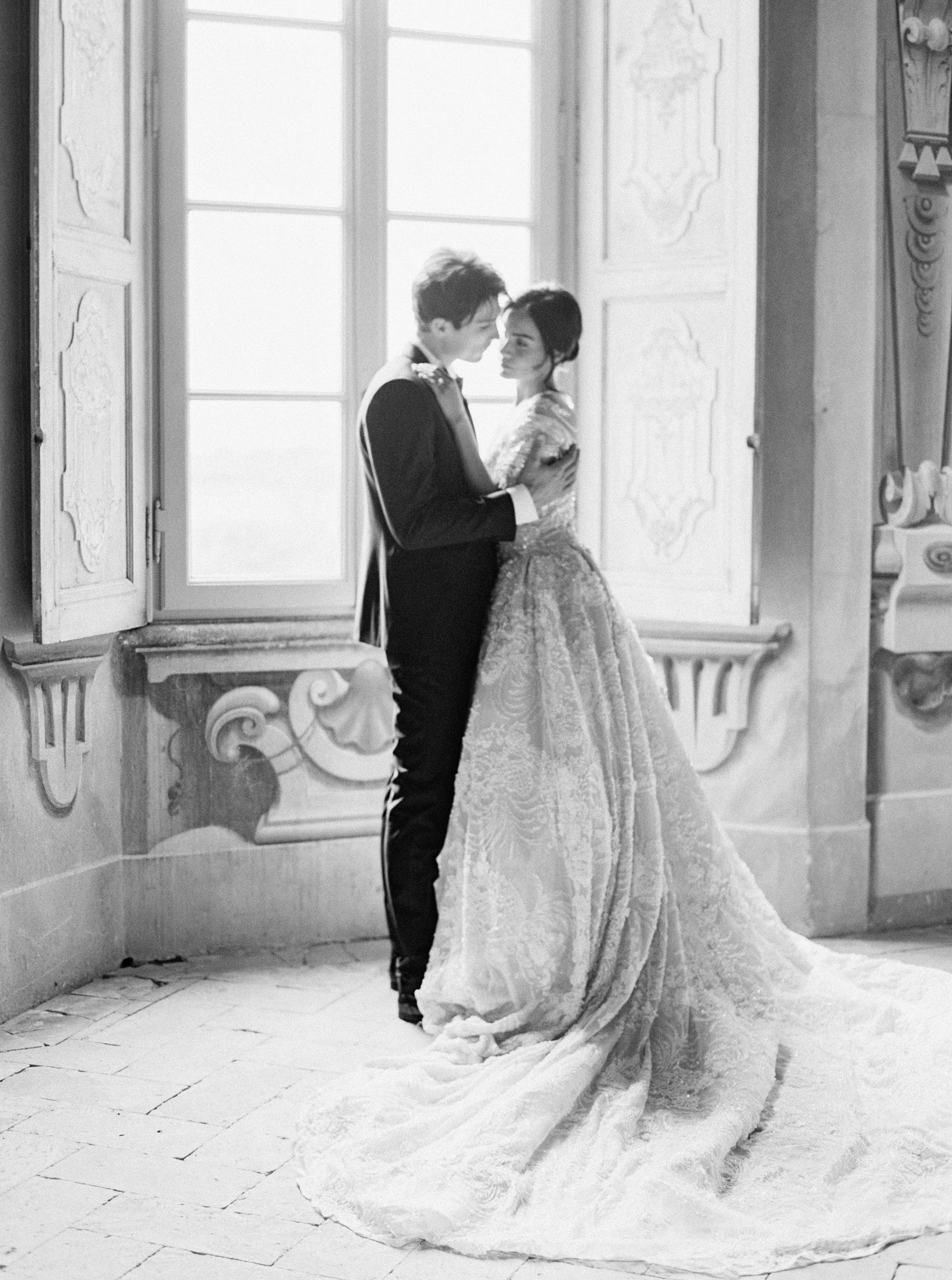 bride and groom in front of window embrace