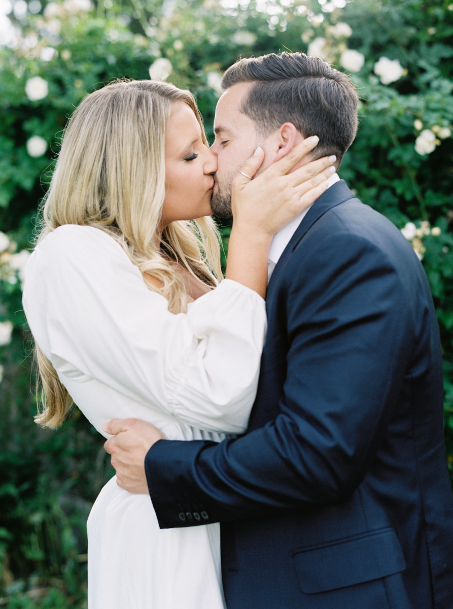 close up kiss with bride to be holding groom to be's face