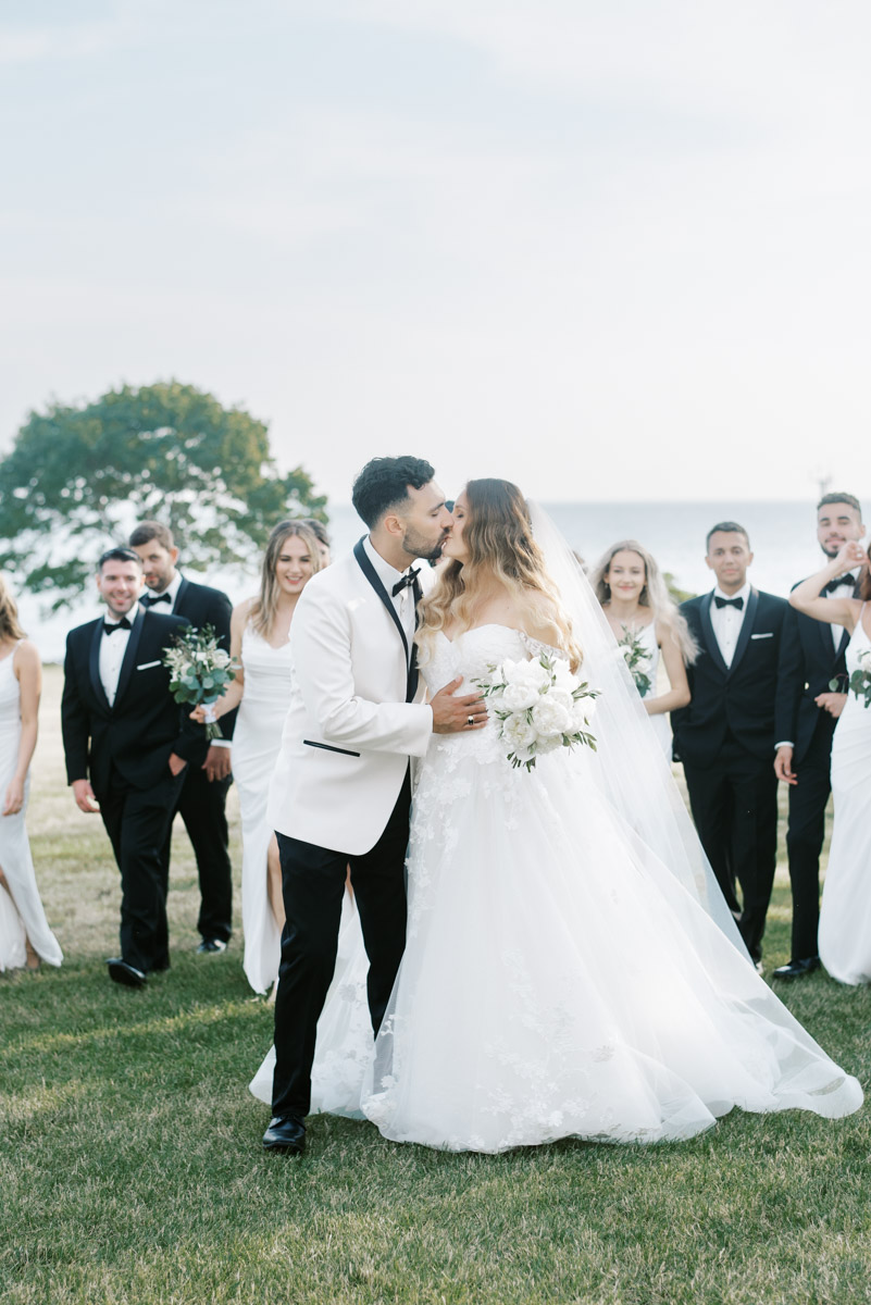 bride and groom kissing with wedding party