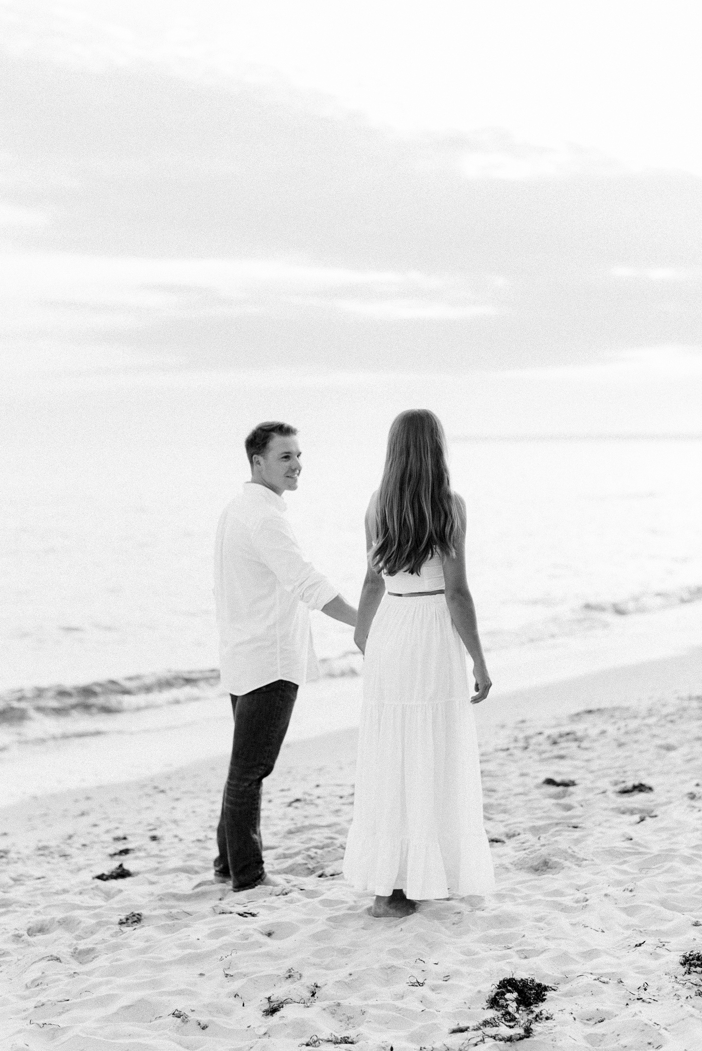 bride and groom walking long beach in black and white