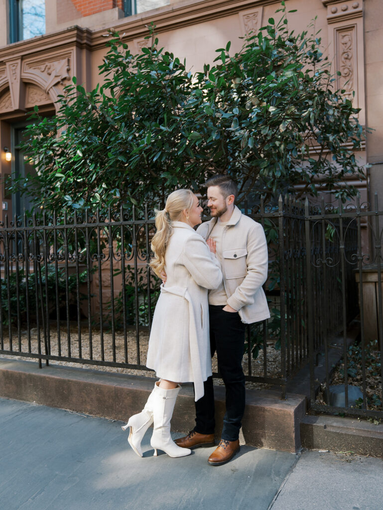 The bride and groom are just engaged and leaning against the fence