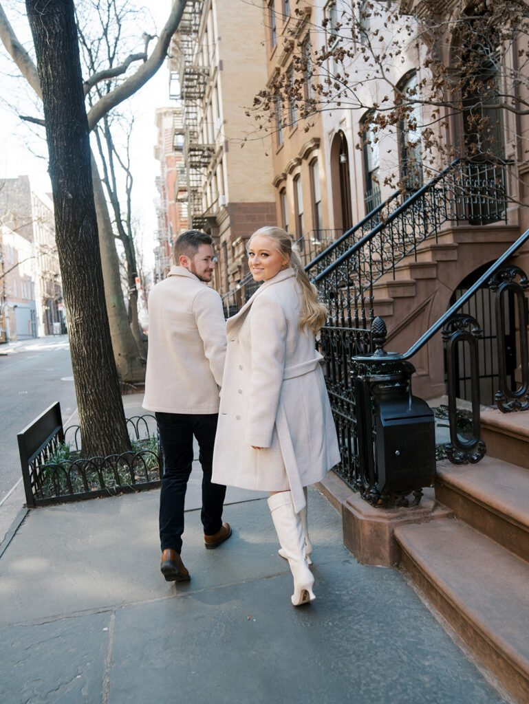 The bride is looking back at the camera while the couple is walking along the streets.