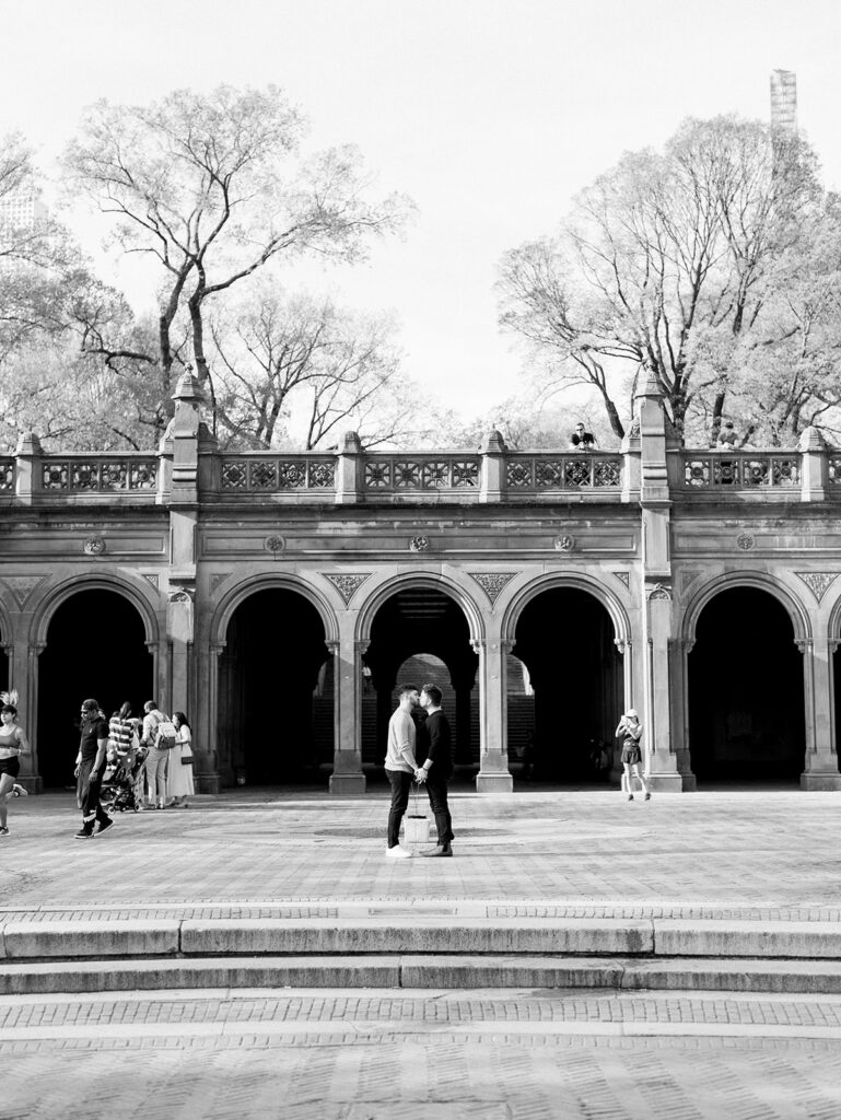 The couple in the middle of Central Park Bethesda Terrace sharing a kiss.