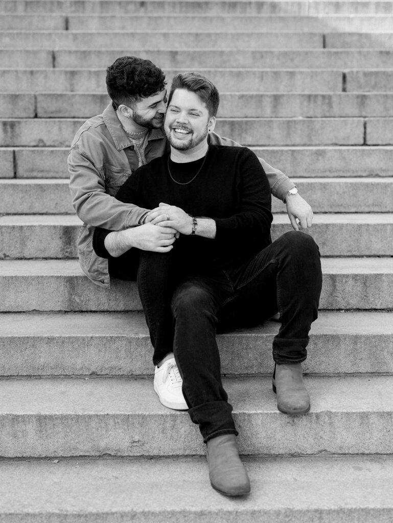 The couple sharing a laugh sitting on the steps of Bethesda Terrace in black and white.