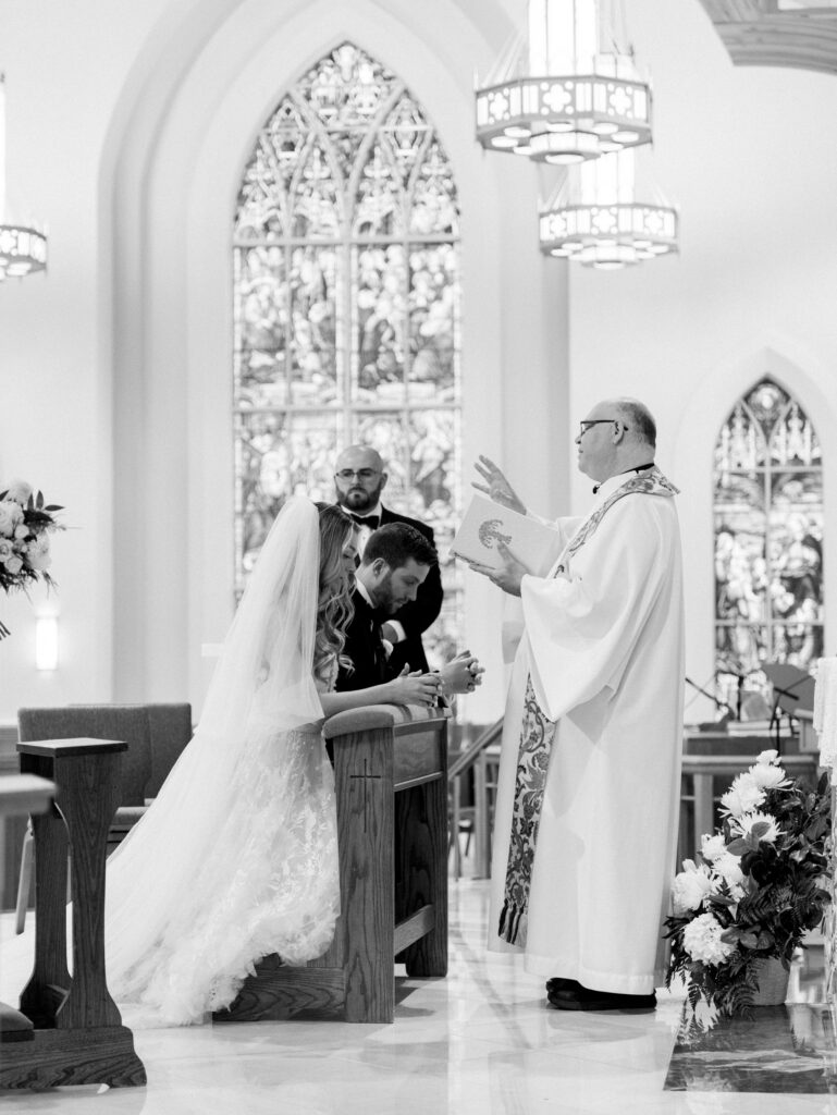 bride and groom receiving blessing in church