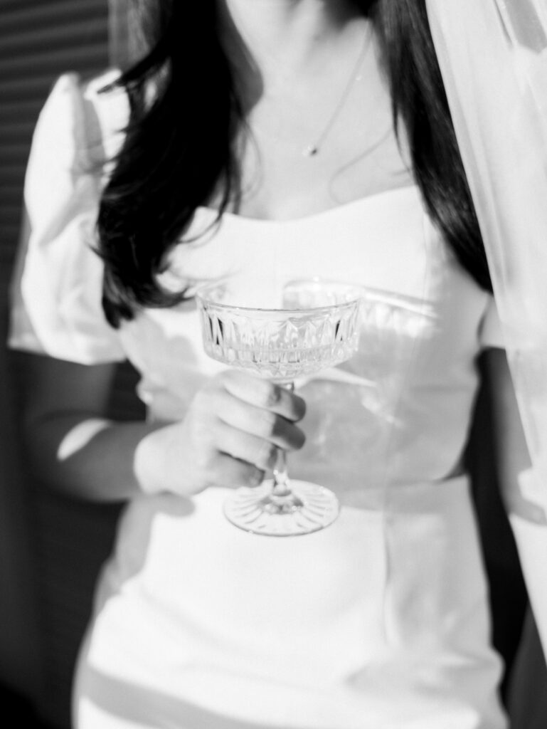 the bride holding her glass of champagne in direct sun during her modern engagement session