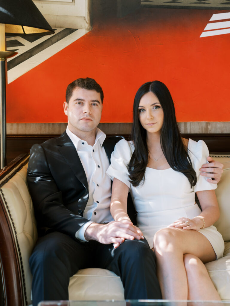 the couple sitting on the couch in the hotel lobby during their modern engagement session