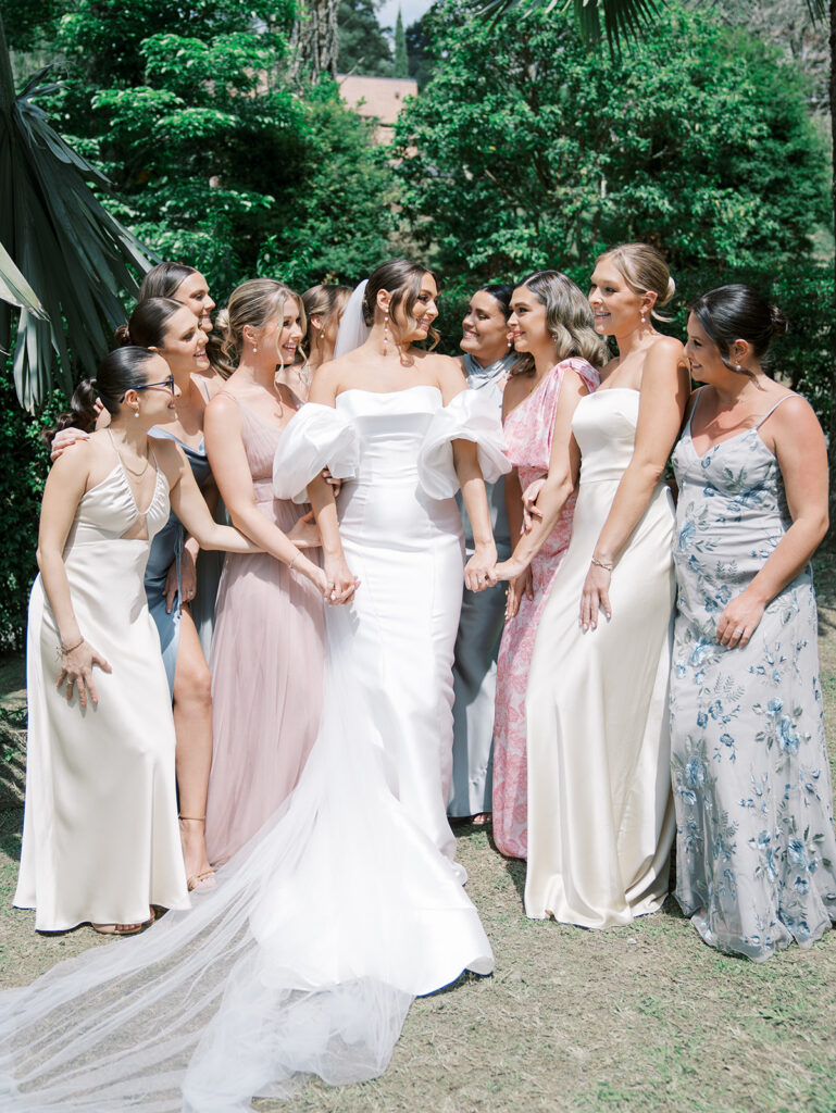 Bridesmaids in the garden in the sunlight looking at each other.
