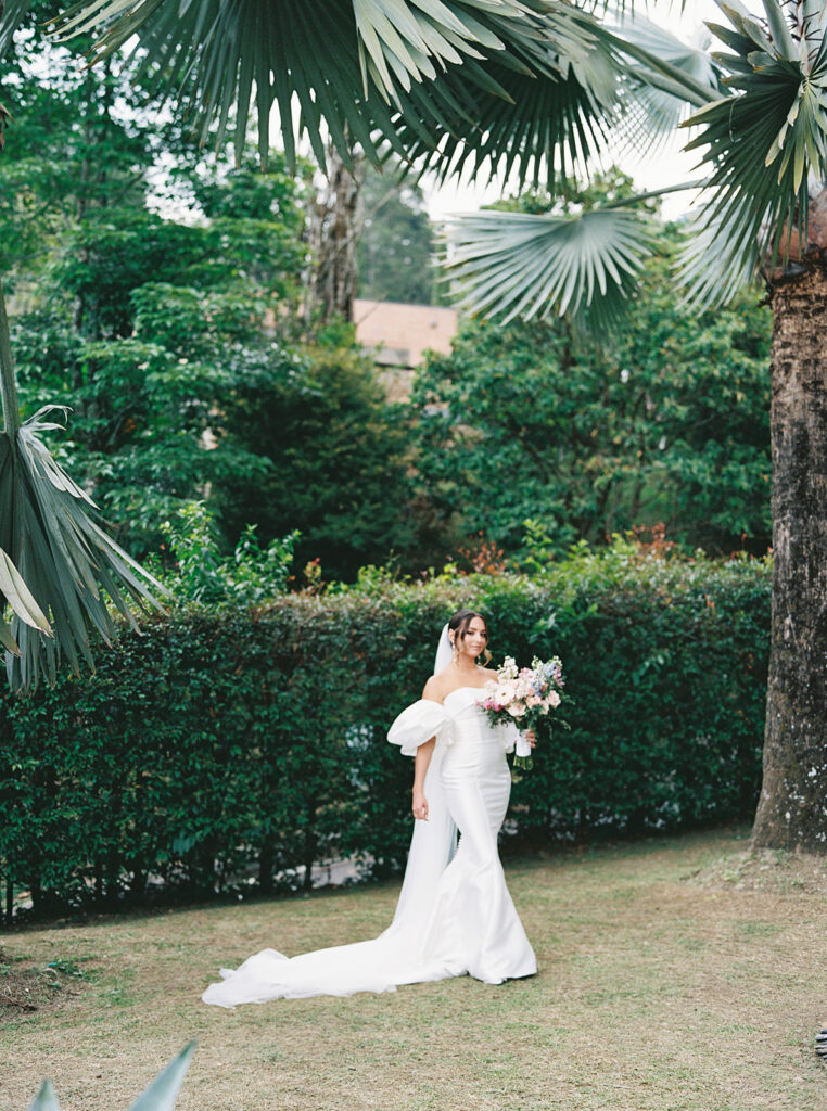 Bride in the gardens at her family home in Colombia posing for a portrait with her bouquet.