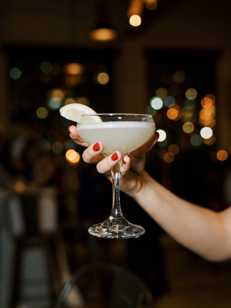 A crafted cocktail being held up by a guest.
