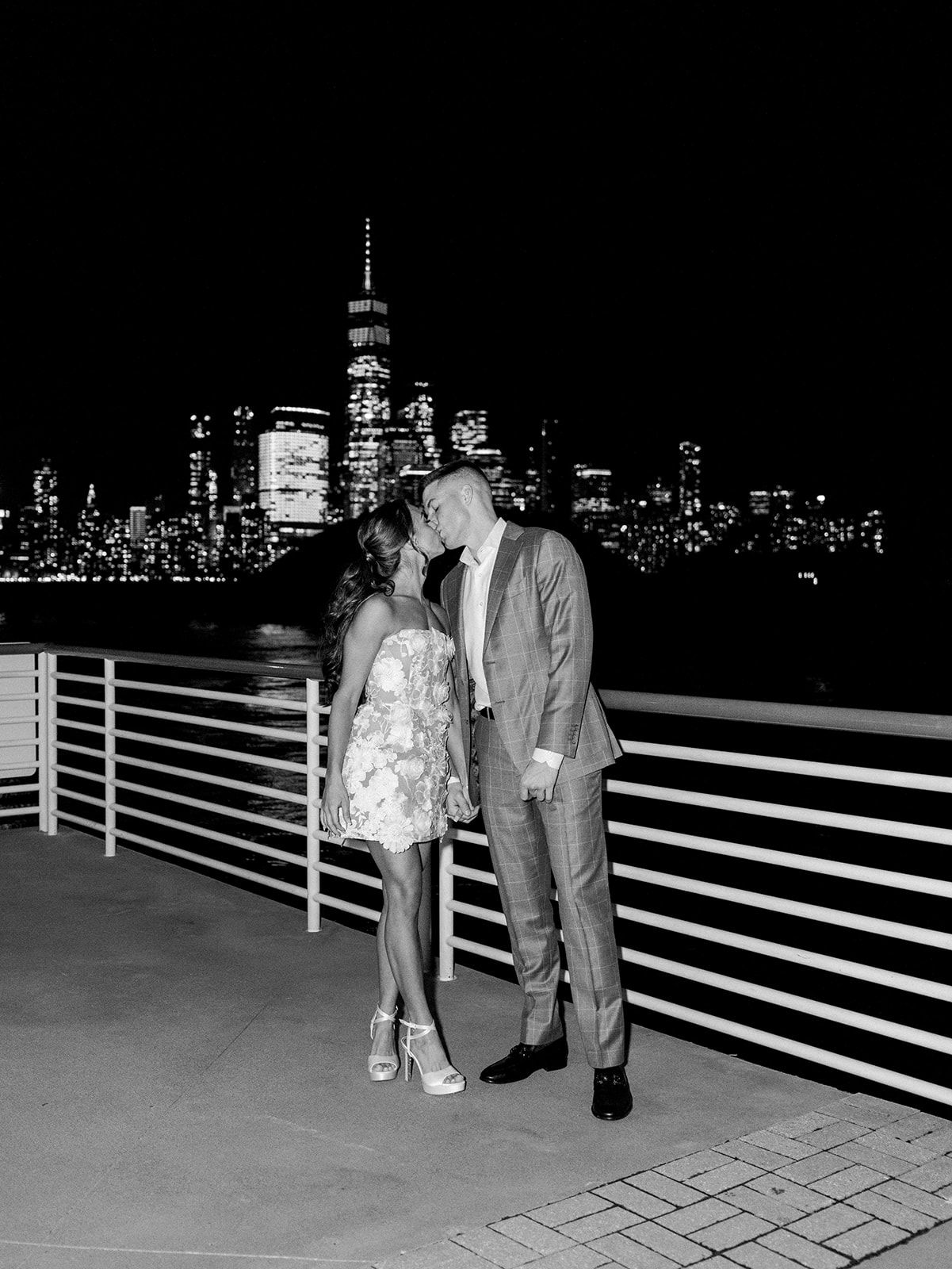 Bride and groom kissing with Manhattan in the background at their Battello Engagement Party.