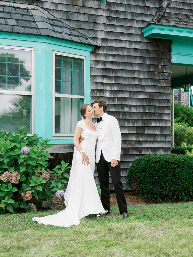 Groom kissing the bride on the cheek in this full body portrait.