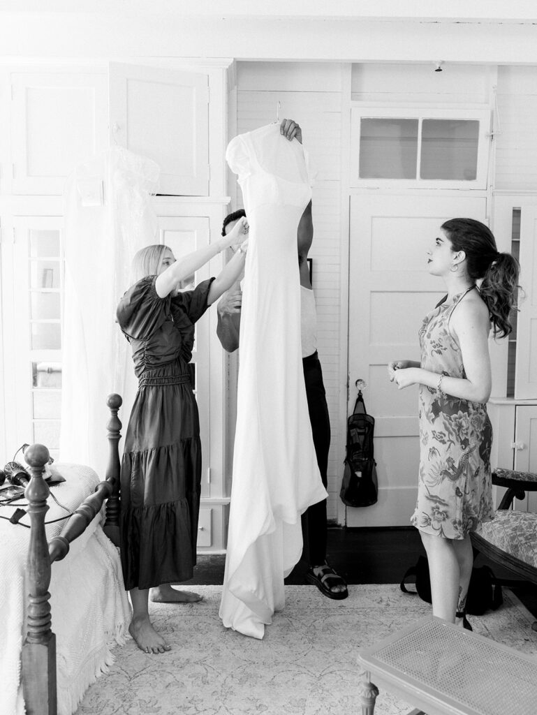 The couple's friends preparing the dress for the bride.