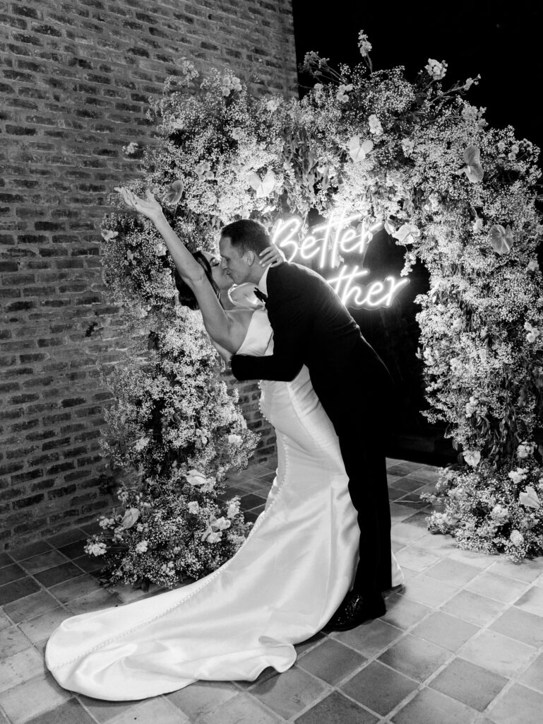 Bride and groom kissing in front of their floral arch at their reception at their Colombia wedding.
