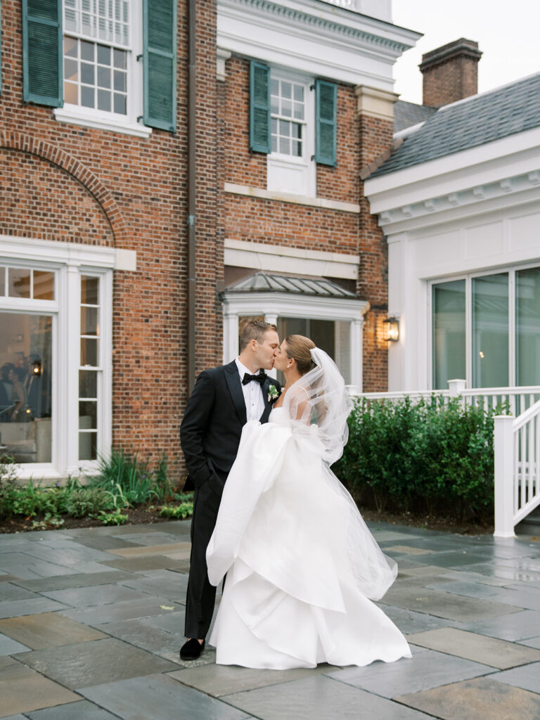 Bride and groom kissing in front of the Coveleigh Club.