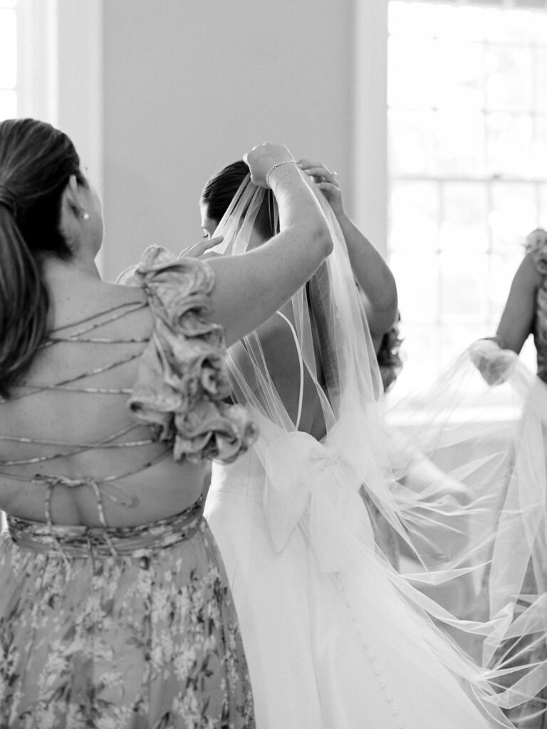 Bridesmaids putting the bride's veil on for her Coveleigh Club Wedding.