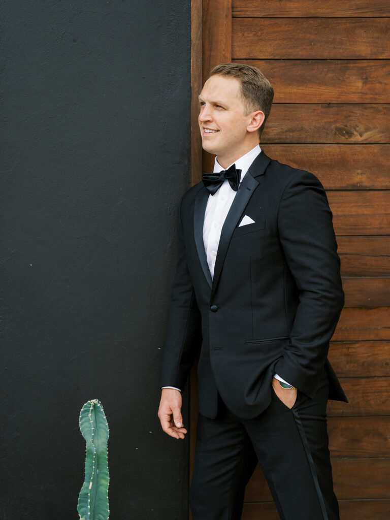 Portrait of the groom against a black wall.