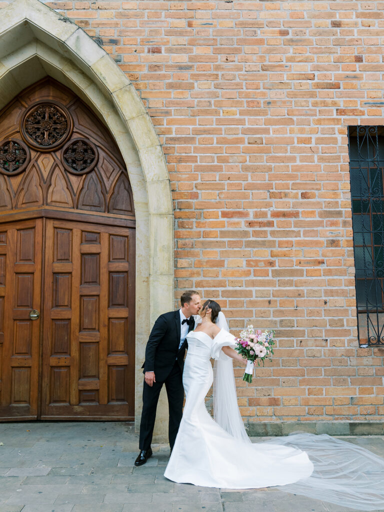 Bride and groom portrait. Bride and groom kissing outside of the church.