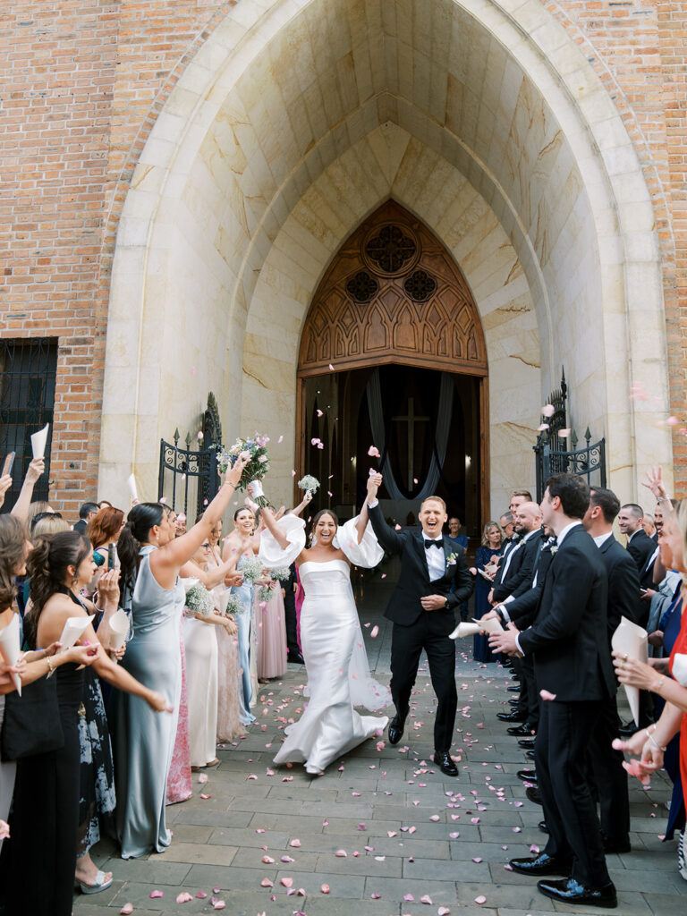 Church exit at this Colombia Wedding with the bride and groom with their arms in the air surrounded by family and friends.