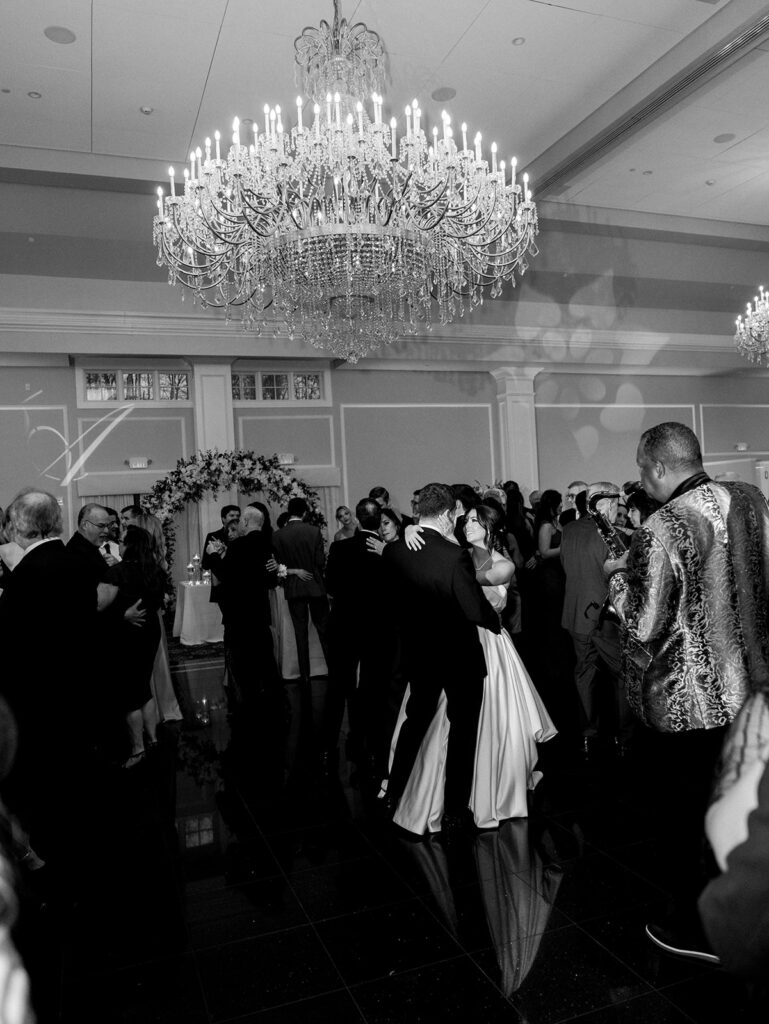The bride and groom share a smile during their first dance while their guests surround them on the dance floor.
