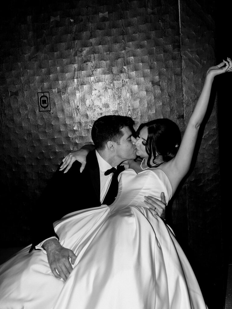 The bride and groom kiss during fun nighttime portraits in the lobby.