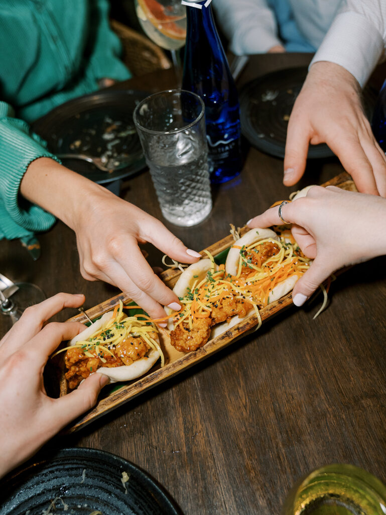 The guests reaching in for appetizers. This is a top down photo of their hands reaching for tacos.