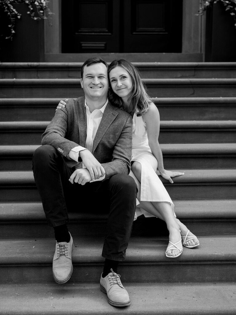 Bride and groom sitting on the steps smiling for the camera during their Greenwich Village Engagement Session.