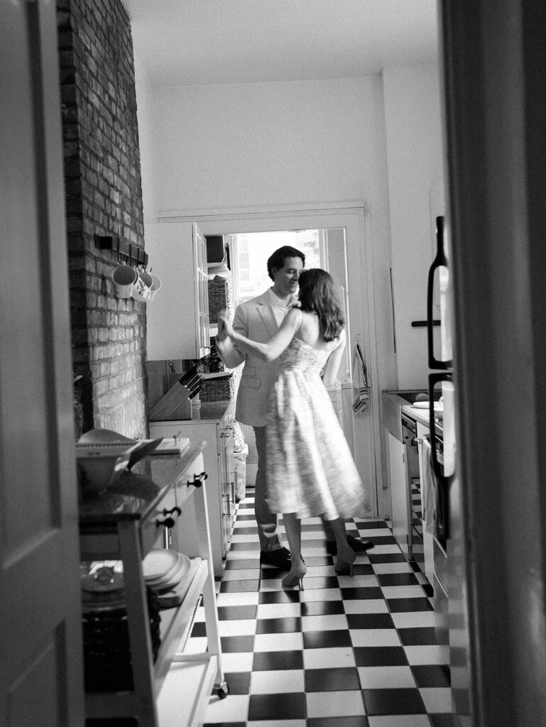 The couple dancing in the kitchen in black and white with some motion blur.