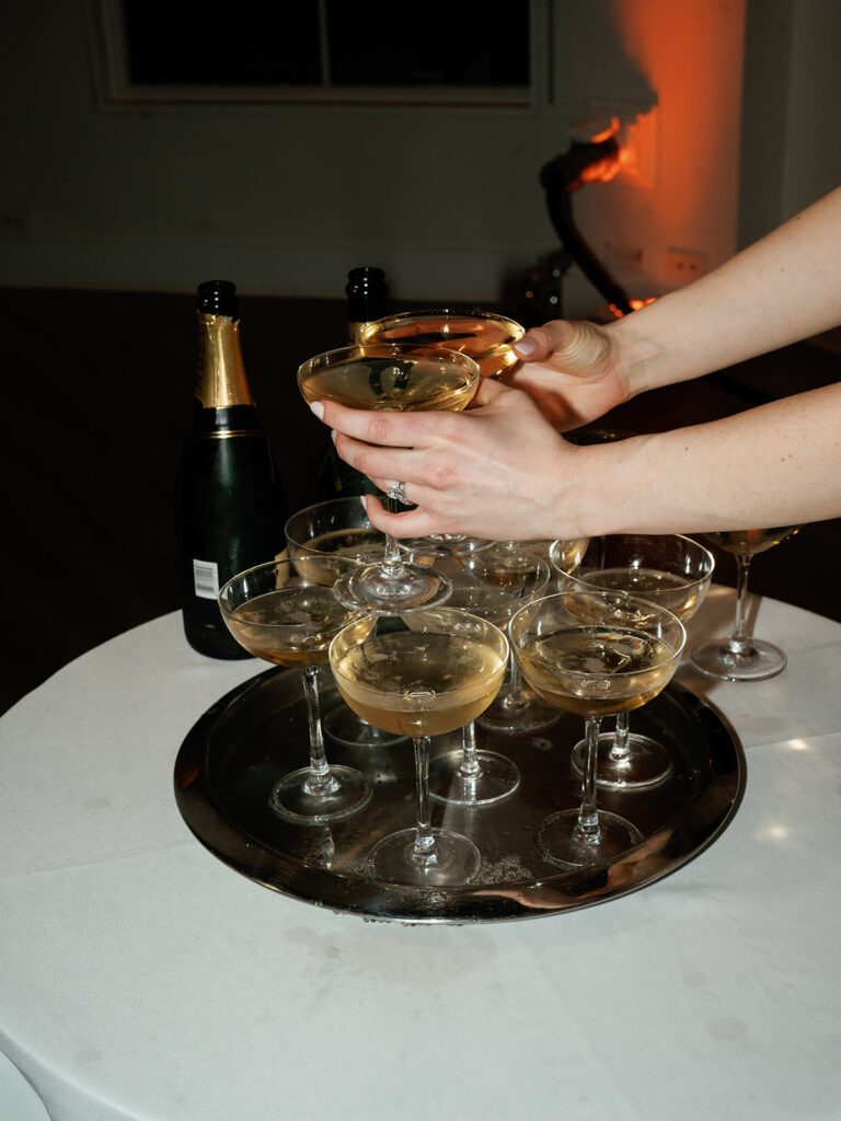 The couple reaching for champagne at their champagne tower.