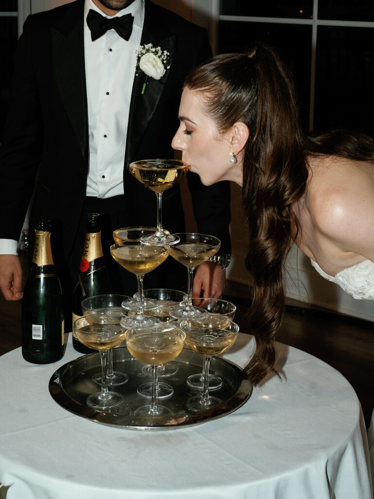 The bride having a sip of champagne from the champagne tower.