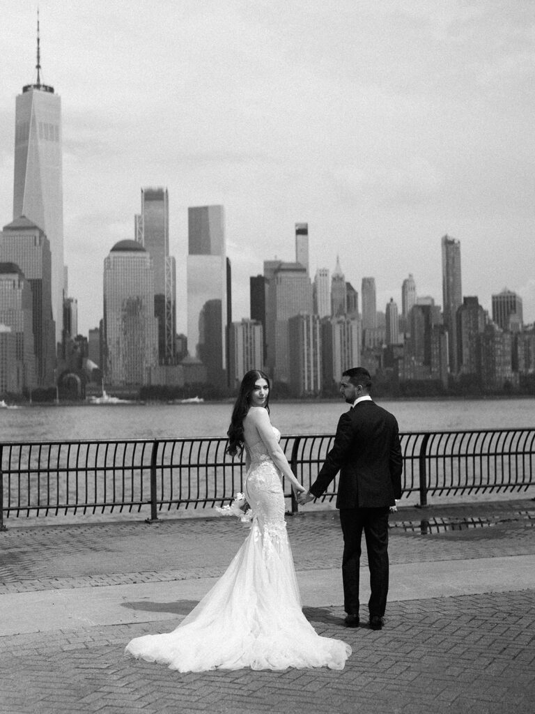 The bride and groom walking away from the camera with the bride looking over her shoulder.