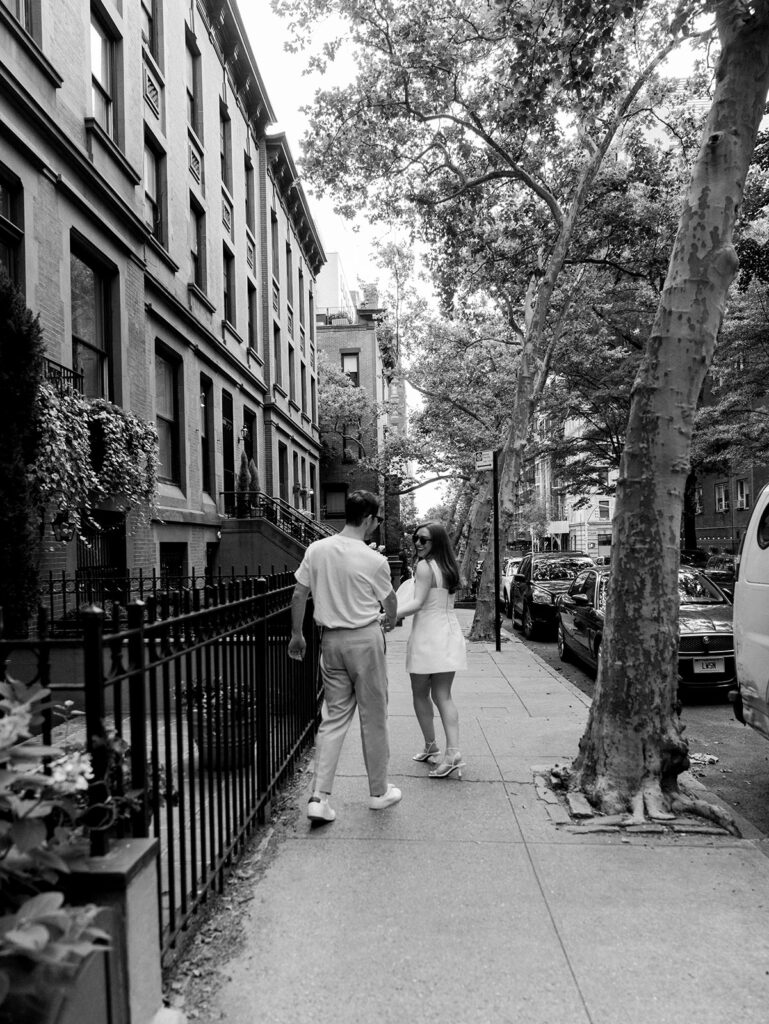 walking together laughing in black and white during their upper east side engagement shoot