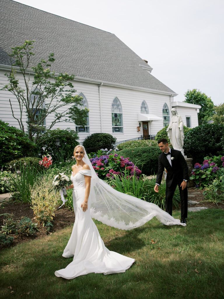 The groom assisting bride with her dress as they get ready for portraits