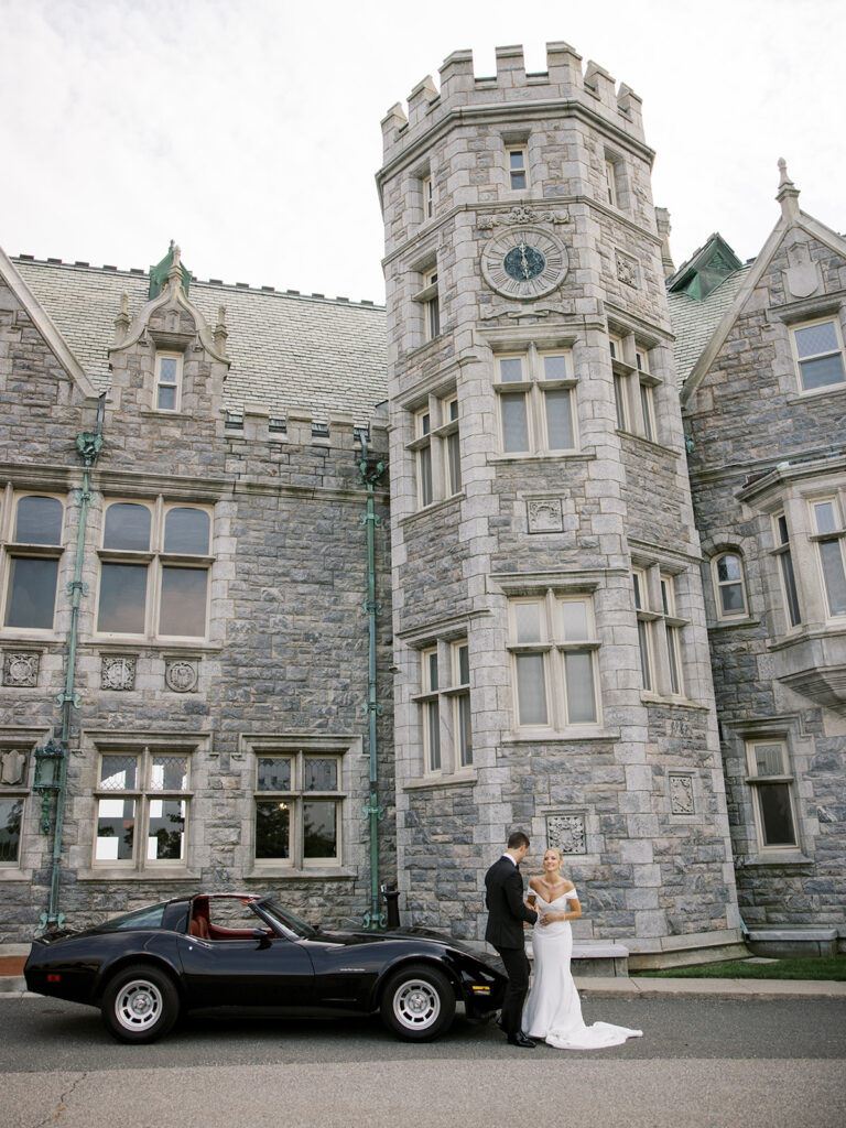 bride and groom posing for portraits with a classic car outside of Avery Point for their Castle Wedding