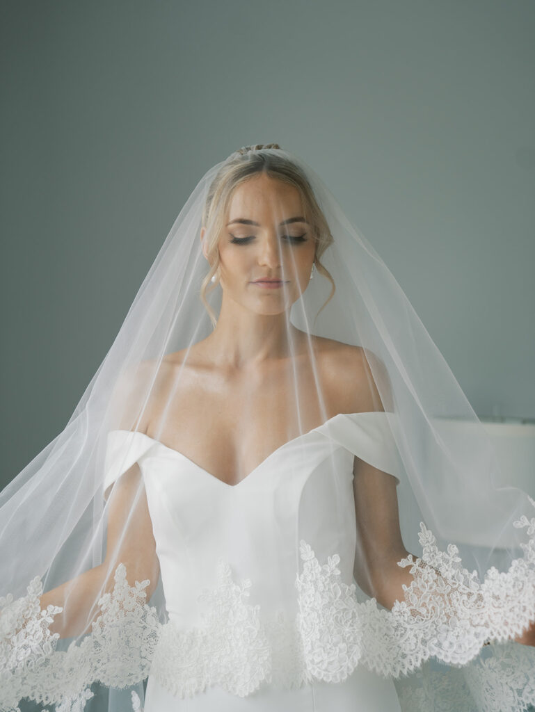 Bride getting ready with her blusher veil over her face and her eyes down