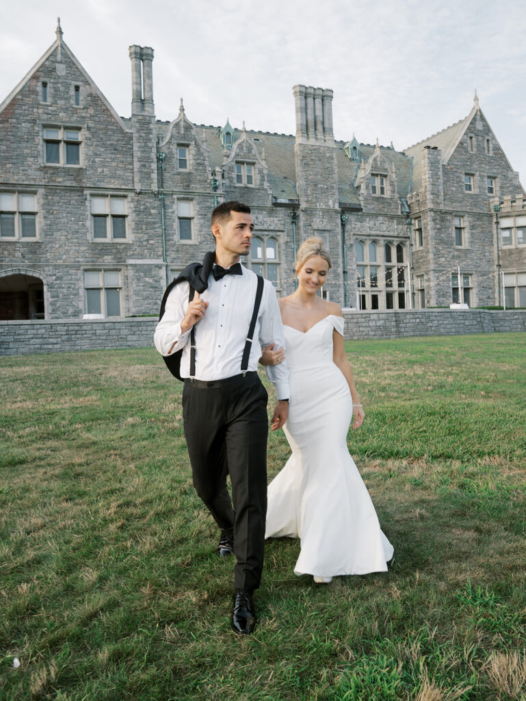 Bride and groom walking away from the castle hand in hand