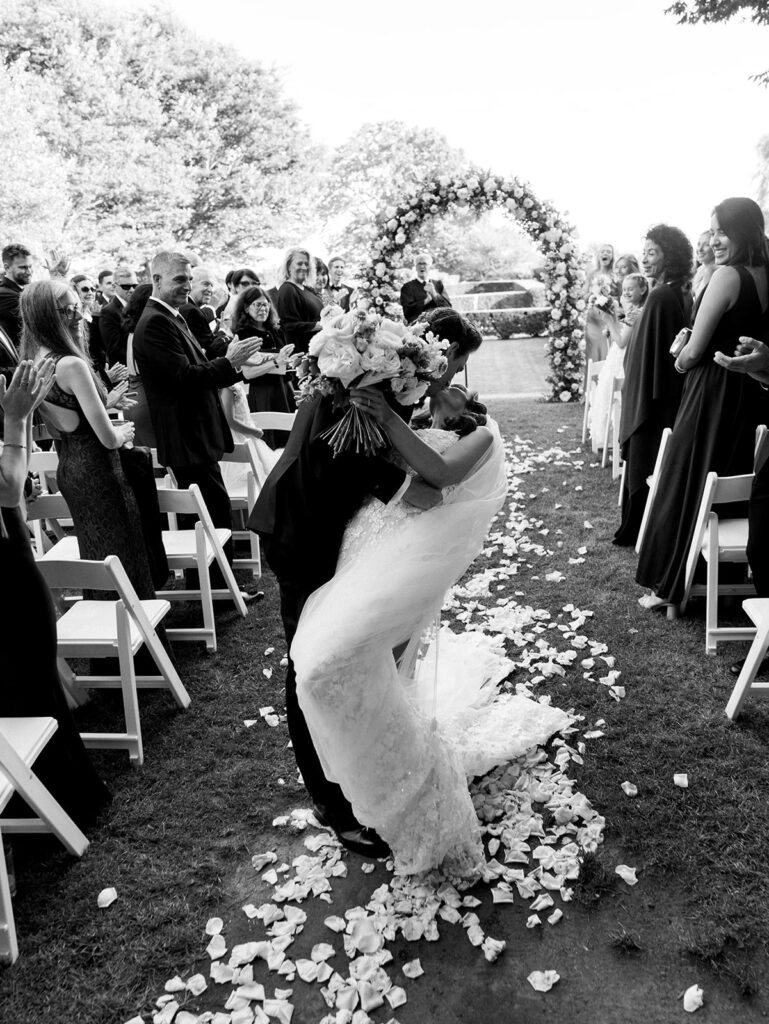 Bride and groom sharing a kiss in the aisle wihle they recess.