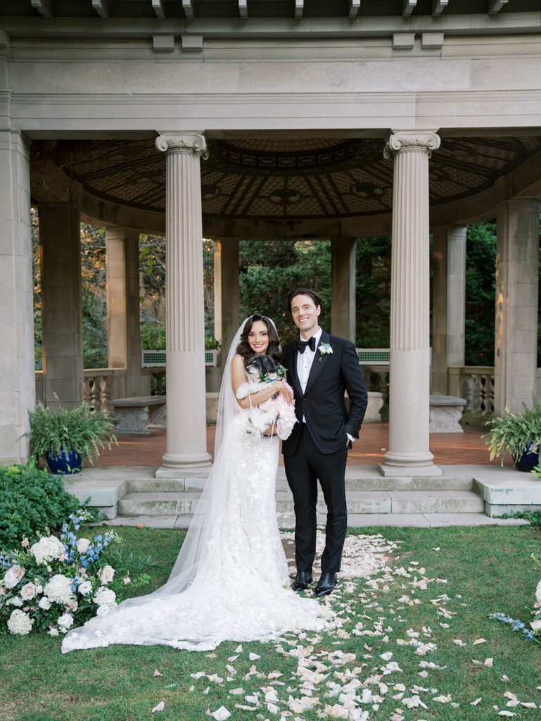 The bride and groom posing for a portrait with their dog.