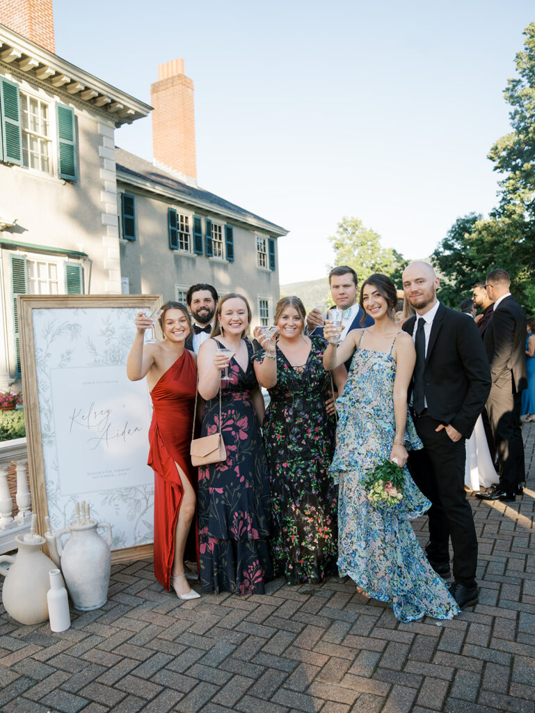 Guests posing for a picture near the welcome sign during cocktail hour.