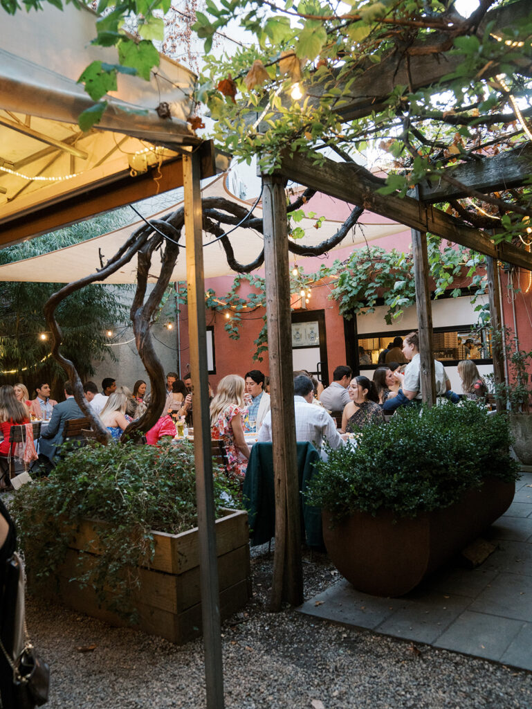 Guests enjoying dinner in a pulled back photo of the restaurant courtyard space.