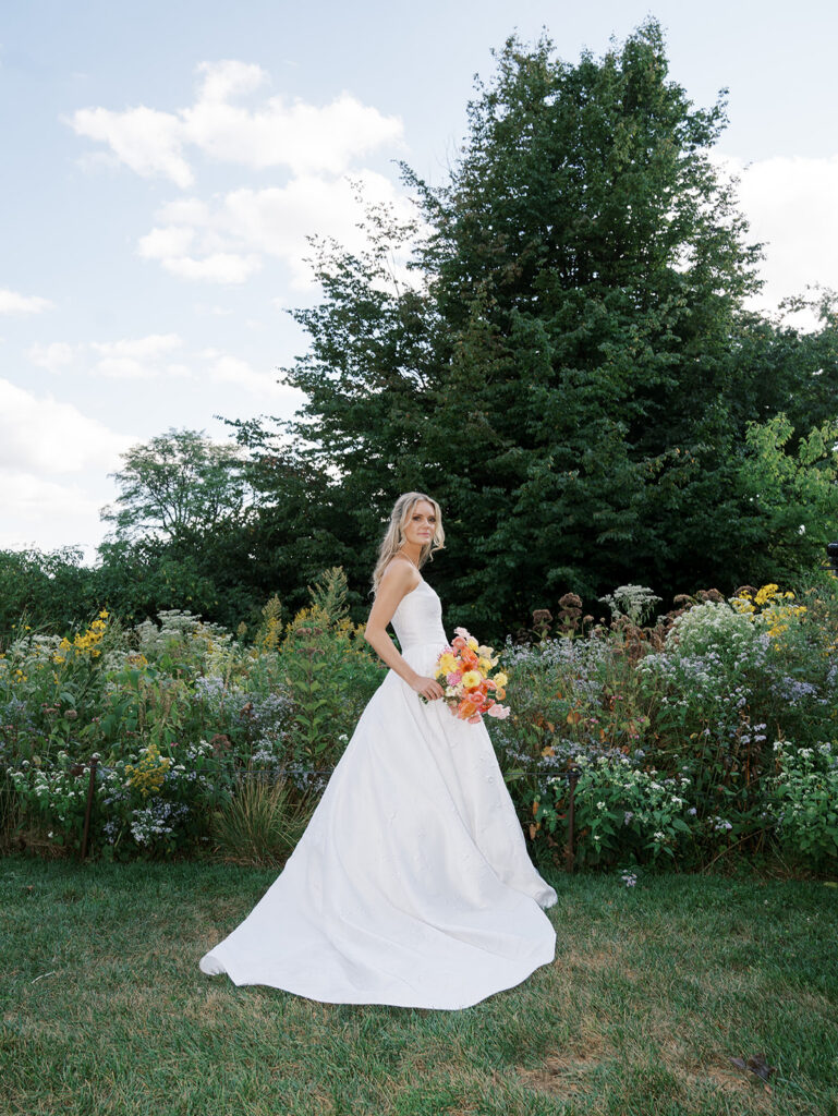 Bride standing in the field at sunset.