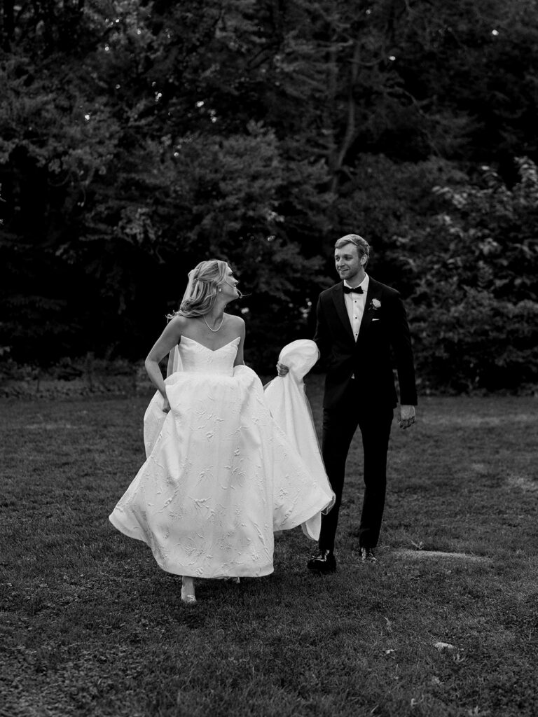 The bride and groom walking happily toward the camera the bride looking over her shoulder at the groom while he holds the train of her gown.