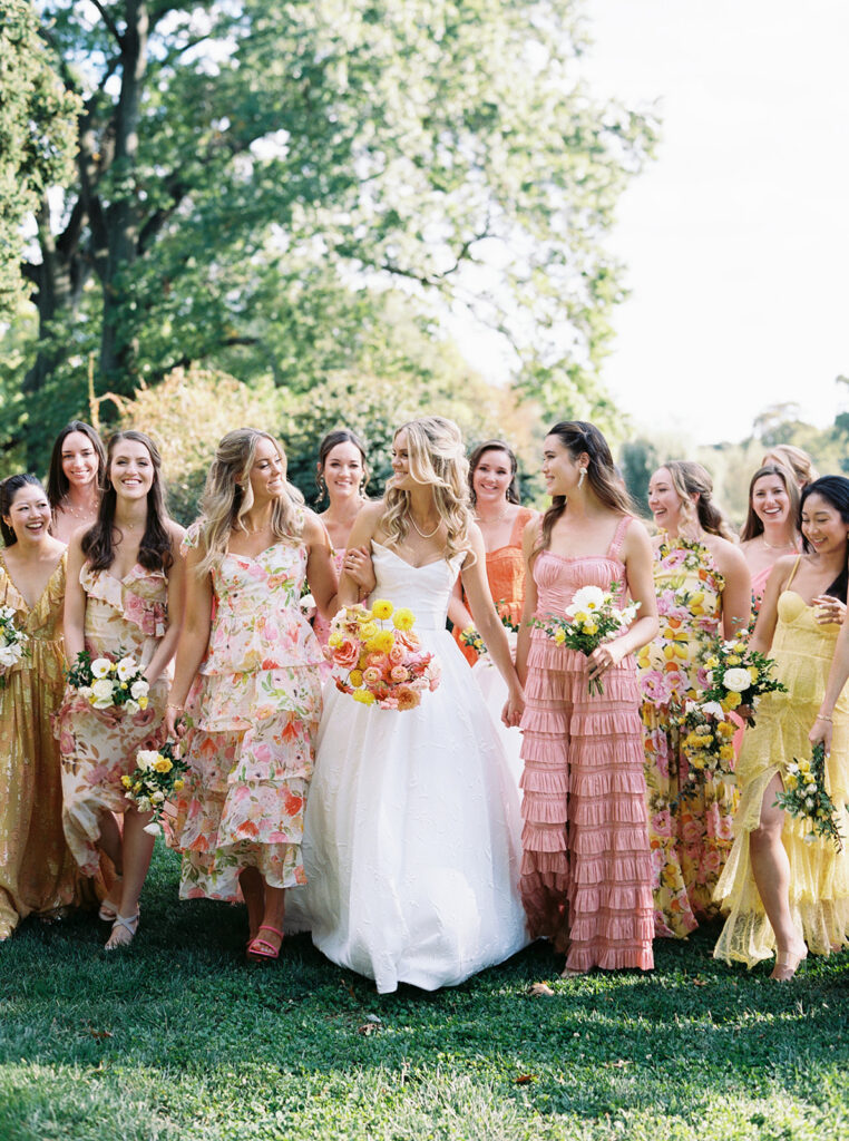 Fiim image of bride and bridesmaids walking together in the gardens laughing.