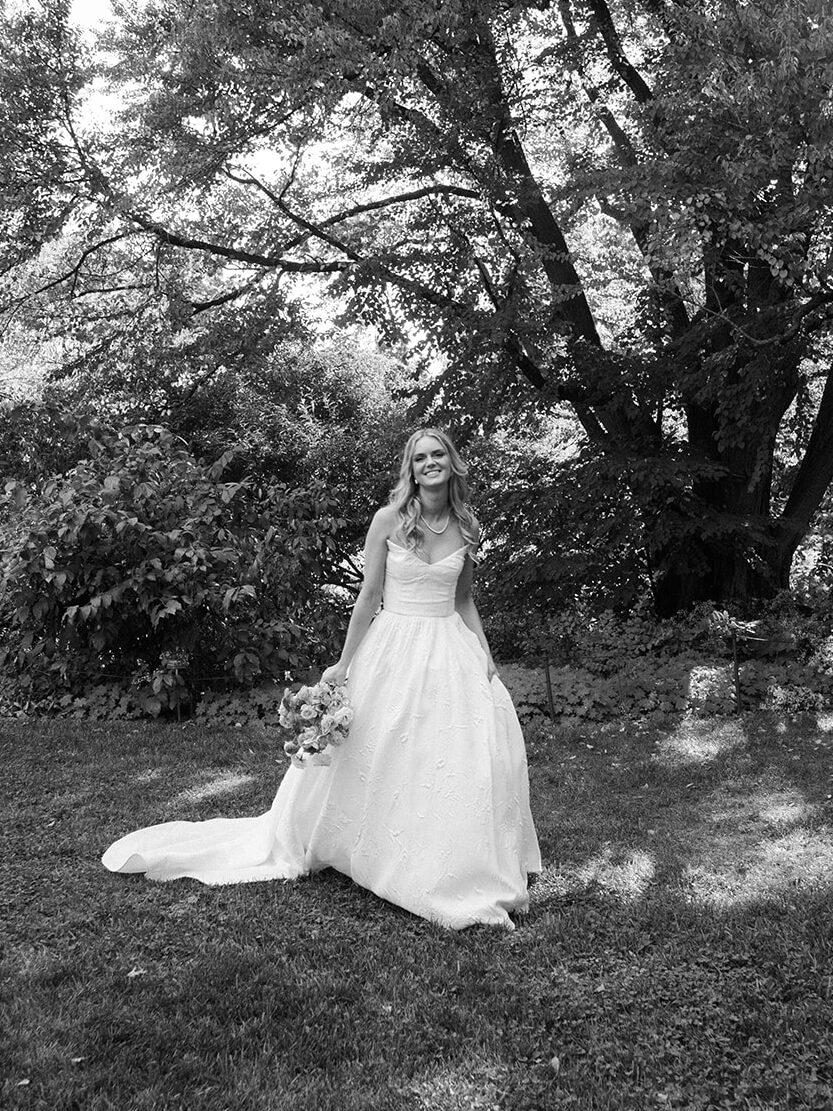 Bride in black and white in the garden laughing.