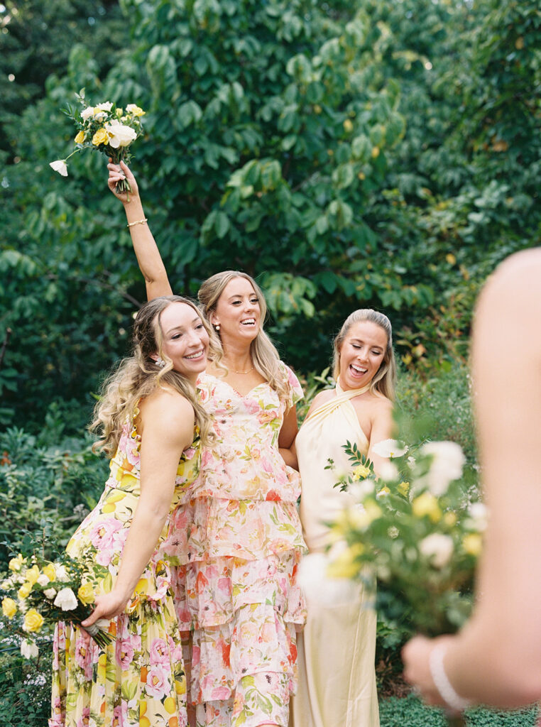 Excited candid of bridesmaids with flowers in the air.