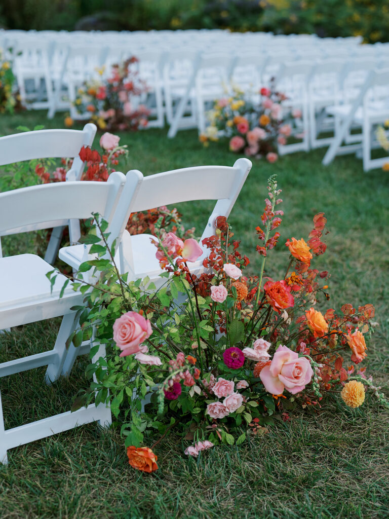 A close up of the floral arrangements along the aisle chairs.