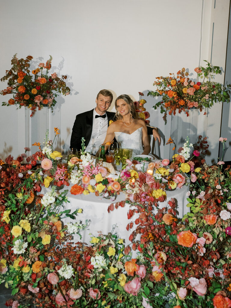 Bride and groom at their head table surrounded by florals.